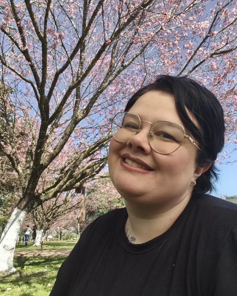 Retrato da psicóloga Bianca Auer em um jardim com cerejeiras
